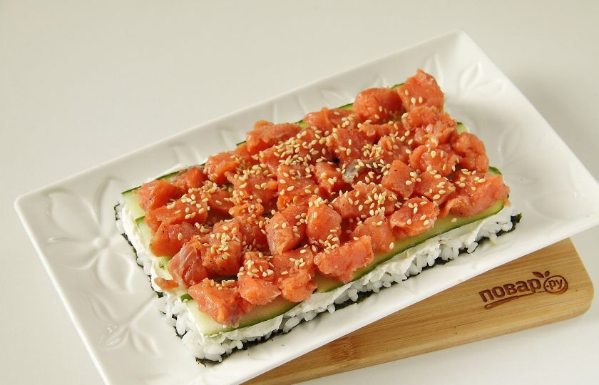 1. Этап. Салат Суши: На огурцы положите кусочки рыбы. Посыпьте рыбу слегка кунжутом.