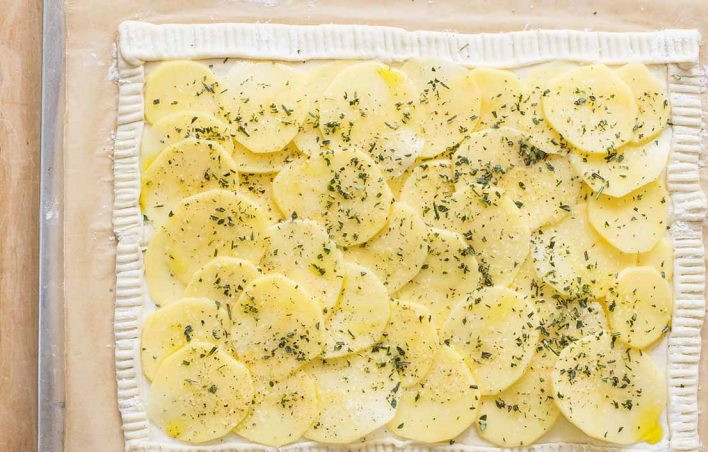 1. Этап. Картофельный тарт: 4. Выложите картошку в миску и полейте столовой ложкой растительного масла, посыпьте измельченными травами (1 столовая ложка), солью и перцем. Выложите картофель на тесто, отступая от края.