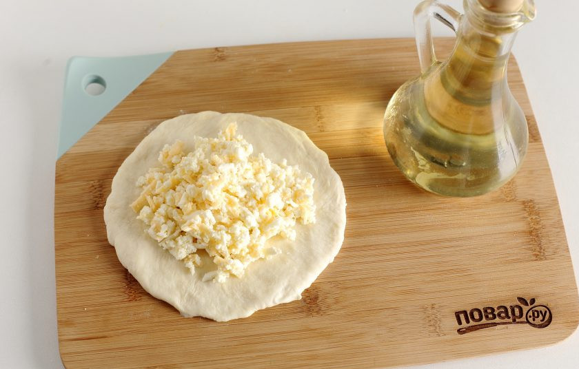 1. Этап. Хачапури на сметане: Обваляйте кусочки в муке и поочередно раскатайте в форме круга. По центру выложите начинку.