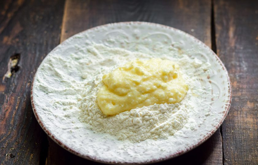 1. Этап. Манники с творогом на сковороде: Переложите пару ложек подготовленной массы в муку, обваляйте и сформируйте лепешку.