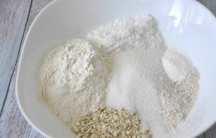 1. Этап. Печенье Анзак: В миску для замешивания теста выложите все сухие ингредиенты: овсяные хлопья, муку, соль, сахар, разрыхлитель (или соду), кокосовую стружку.