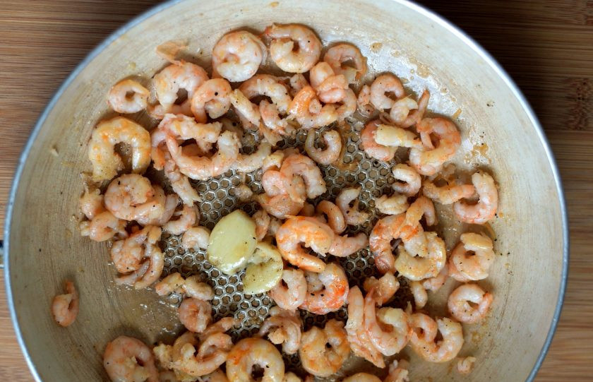 1. Этап. Зеленый рулет с креветками и болгарским перцем: Тем временем займемся начинкой. Креветки очистить и обжарить на ложке масла в течение 2 минут с придавленным зубчиком чеснока. Посолить и поперчить креветки по вкусу. Перцы прогреть в микроволновке и снять с них кожицу.