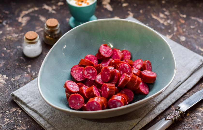 1. Этап. Салат Ежик с колбасой: Колбасу выбирайте самую вкусную, копченую. Нарежьте колбасу небольшими кусочками и переложите в салатник.