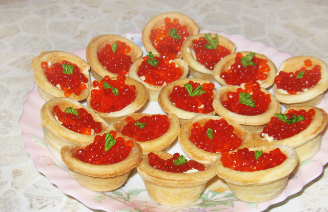 1. Этап. Тарталетки с икрой и маслом: 3. Вот, собственно, и все. Осталось наполнить каждую тарталетку икрой и можно смело подавать закуску на стол. Украсить можно листьями салата или веточкой свежей зелени.