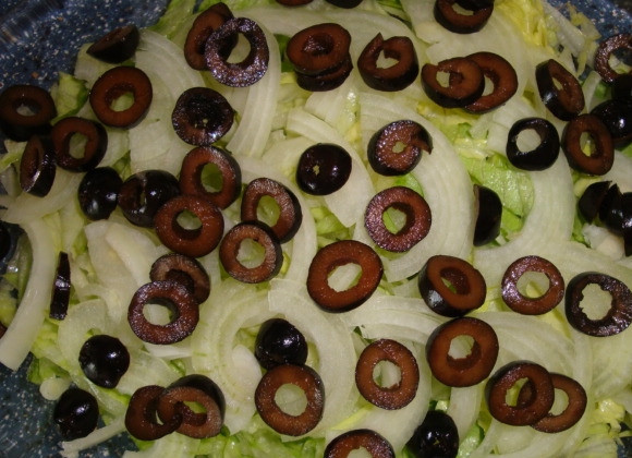 1. Этап. Cалат с фетой и оливками: Оливки нужны без косточек. Нарежьте их колечками и выложите на лук.