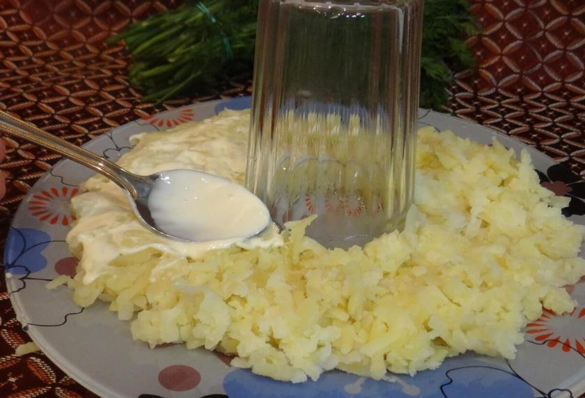 1. Этап. Салат Гранатовый браслет: 5. Берем блюдо и в середину ставим стакан (в конце мы его уберем и получится красивое кольцо). Первым слоем выкладываем тертый картофель и промазываем майонезом.