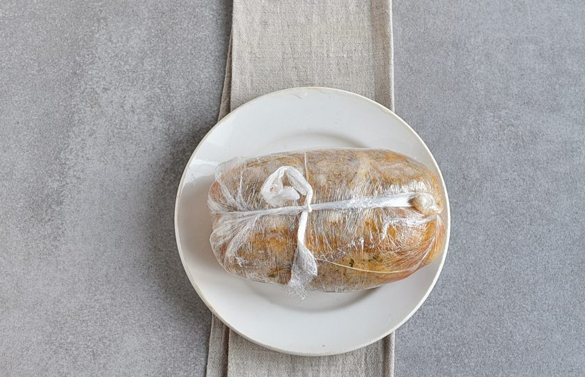 1. Этап. Домашняя ветчина из курицы: Теперь ветчину нужно остудить и еще уплотнить. Можно выложить ветчину под небольшой груз между двумя досочками. Я заворачиваю горячий батончик ветчины в пищевую стрейч-пленку, туго закручивая концы и связывая их, чтобы крепко «спеленать». Отправьте сверток в холодильник до полного остывания.