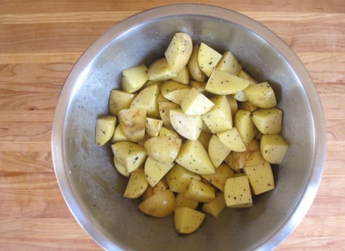 1. Этап. Куриные ножки с картофелем и розмарином: 2. Картофель почистите и нарежьте крупными кубиками. Затем смешайте с измельчённым розмарином и очищенным чесноком. Добавьте масло, соль и перец.