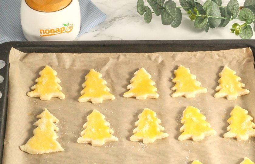 1. Этап. Творожное печенье «Елочки»: Смажьте заготовки желтком с помощью силиконовой кисточки и присыпьте сахаром. Отправьте в духовку на 7-10 минут. Обязательно на верхний уровень и следите за выпечкой, так как у елочек подгорают края.