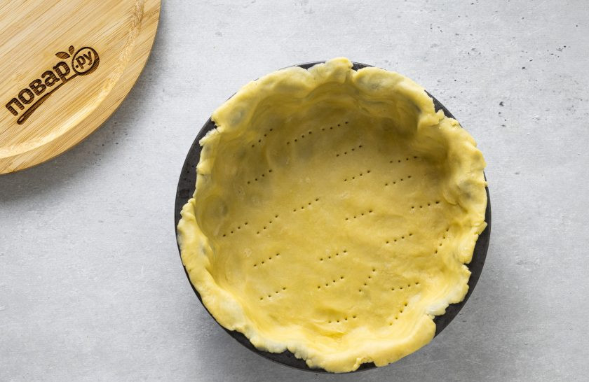 1. Этап. Вегетарианский пирог с вишней: Раскатайте половину теста на плоской поверхности. Переложите в форму для выпечки. Прижмите края к бортикам. Дно пирога наколите вилкой.