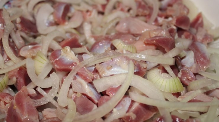 1. Этап. Куриные желудки по-деревенски: Затем перемешайте в глубокой миске куриные кусочки с луком.