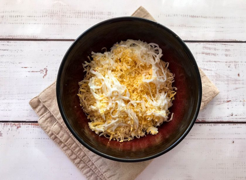 1. Этап. Салат Одуванчик с сыром: Возьмите 2 яйца, очистите от скорлупы, натрите и добавьте к сыру.