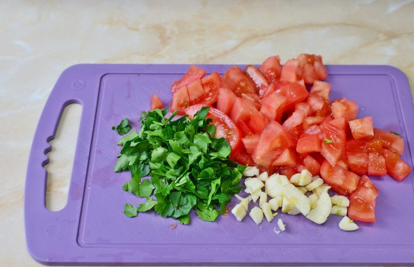 1. Этап. Цыпленок по-охотничьи: Нарежьте помидоры. Измельчите петрушку и чеснок.