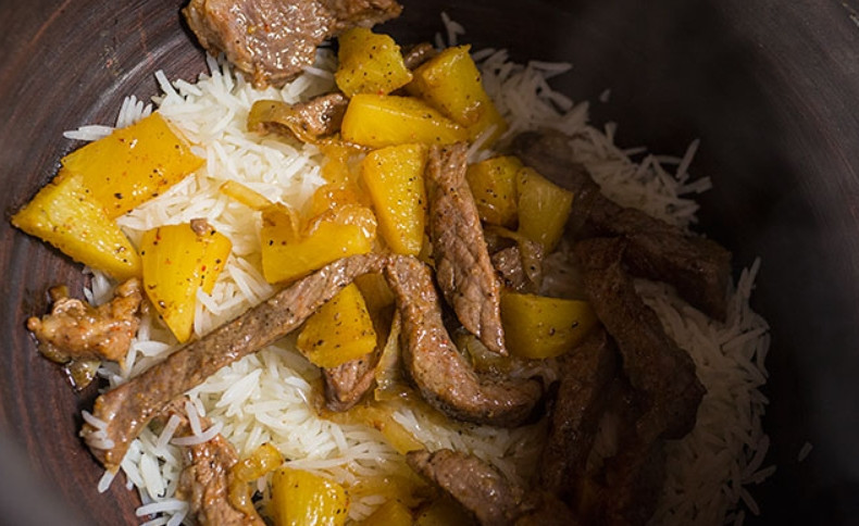 1. Этап. Плов в духовке со свининой: Параллельно отварите в подсоленной кипящей воде рис. Затем откиньте его на дуршлаг. Переложите рис в горшок для запекания, добавьте мясо с луком и ананасами. Сверху вылейте сок со сковороды, добавьте изюм. Поместите горшочек в духовку, обязательно накрыв его крышкой. Запекайте 2 часа при 150 градусах.