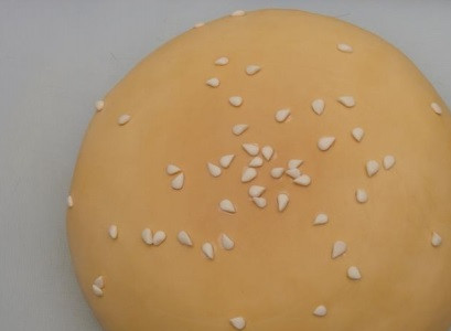 1. Этап. Торт Гамбургер: 6. Верхний корж окрасить с помощью пищевого красителя в слегка желтоватый цвет. Из мастики вырезать небольшие кусочки, имитирующее семена кунжута.