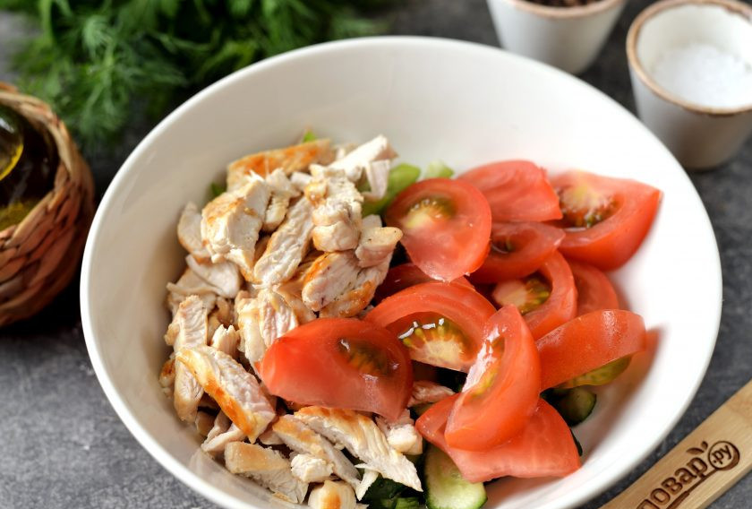1. Этап. Овощной салат с курицей и фасолью: Вырежьте на помидоре место плодоножки, нарежьте его и остывшее куриное филе такими же тонкими ломтиками, переложите в миску.