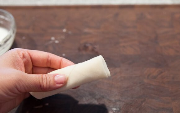 1. Этап. Спринг роллы с курицей: 10. Главный секрет, как сделать спринг роллы с курицей плотным и не дать им развернуться, заключается в использовании крахмала с водой. Смажьте края, плотно их прижмите.