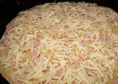 1. Этап. Пицца с ветчиной и ананасами: 4. Нанесите на тесто сырный соус. Сверху уложите слой ананасов, ветчины. Посыпьте тертым сыром.