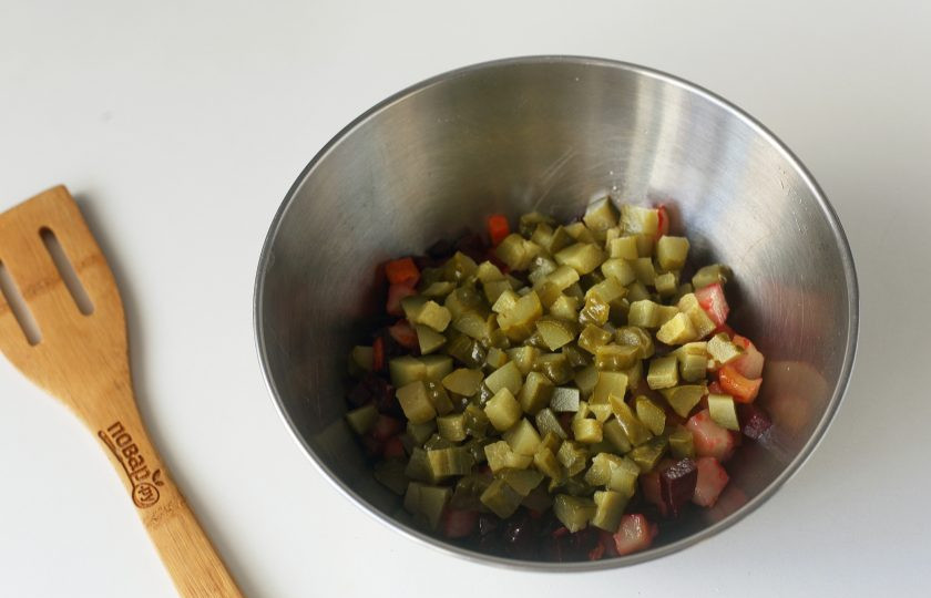 1. Этап. Винегрет из запеченных овощей: Переложите остывшие овощи в глубокую миску и добавьте соленые огурцы, нарезанные примерно такими же кубиками.