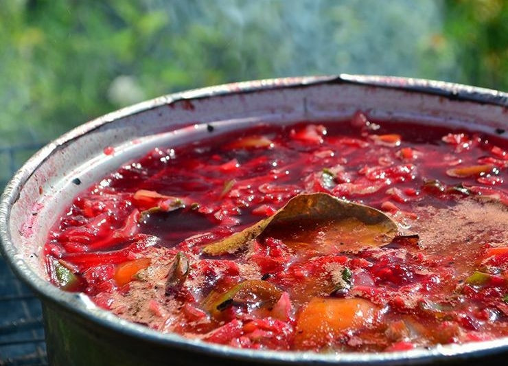 1. Этап. Борщ в казане на костре: Картофель нарежьте небольшими кусочками. Добавьте его в кастрюлю вместе с зажаркой, измельчённым острым перцем и свеклой. Посолите, поперчите, добавьте лавровый лист.