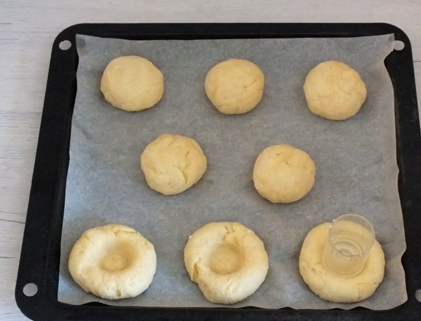 1. Этап. Булочки с вареньем без дрожжей: Противень застелите бумагой. Выложите заготовки, с помощью стаканчика сделайте посередине выемки.