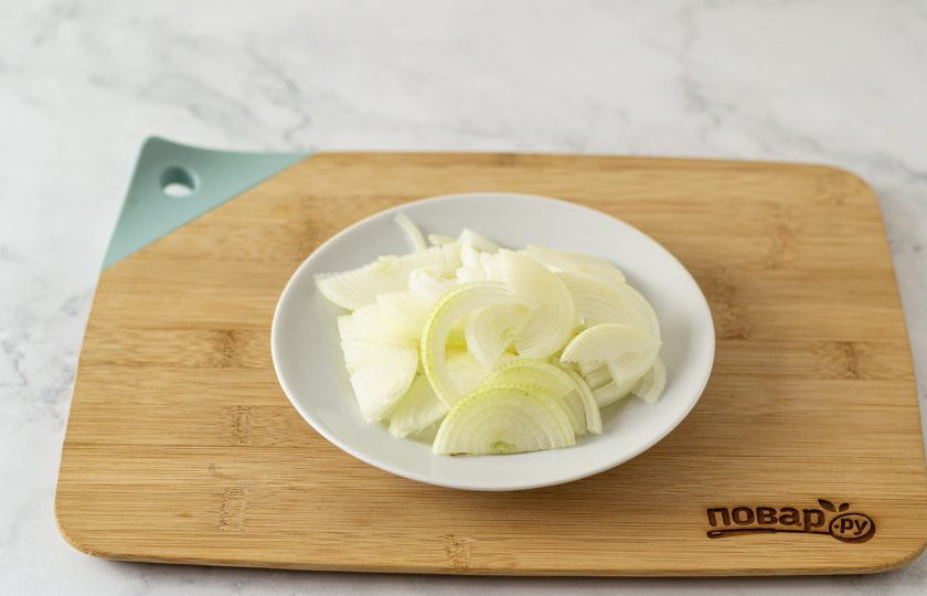 1. Этап. Салат с краснокочанной капустой: Лук нарежьте тонкими полукольцами. Переложите лук в глубокую миску. Залейте кипятком и оставьте на 5 минут.