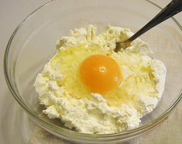 1. Этап. Оладьи из творога и кефира: Выкладываем творог в миску. Растираем его с яйцом, сахаром и солью. Творог желательно брать сухой и рассыпчатый. Если творог будет жидким, то он даст воду. Может потребоваться большее количество муки.