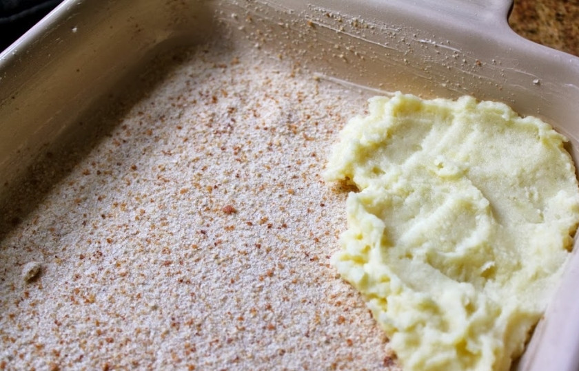 1. Этап. Пирог с моцареллой и ветчиной: Шаг 6. Присыпьте сухариками блюдо для выпечки. Выложите туда 1/3 часть картофельной массы.