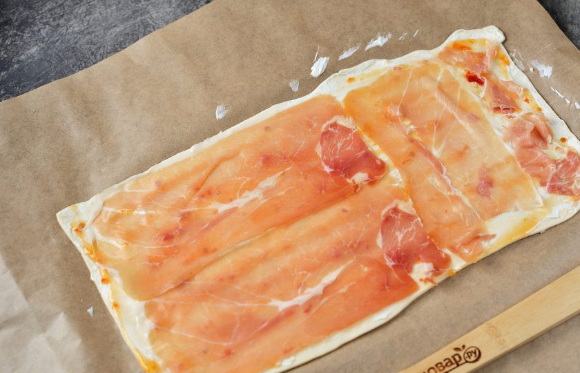 1. Этап. Канапе «Ёлочка» из слоеного теста: Выложите слой любого тонко нарезанного сыровяленого мяса.