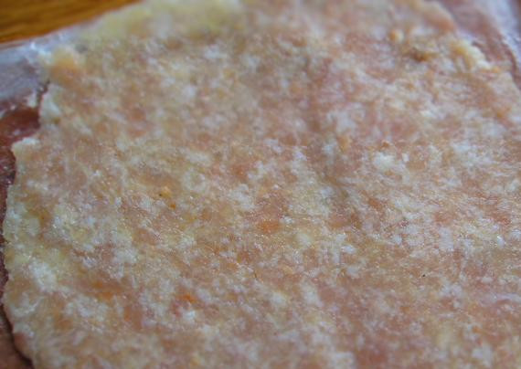 1. Этап. Начинка для бризолей: Расстилаем на столе целлофановую пленку, кладем на нее мясной шарик, накрываем его сверху еще одной пленкой и раскатываем фарш в тонкую лепешку.