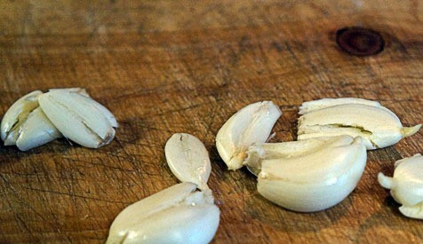 1. Этап. Курица с овощами в духовке: Зубчики чеснока слегка раздавить ножом и разрезать каждый на две-три части.