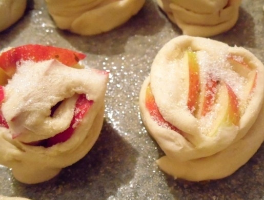 1. Этап. Яблочные булочки: Разогрейте духовку до 180 градусов. Противень застелите пергаментной бумагой. На неё уложите булочки. Посыпьте их оставшимся сахаром и оставьте на 15 минут.