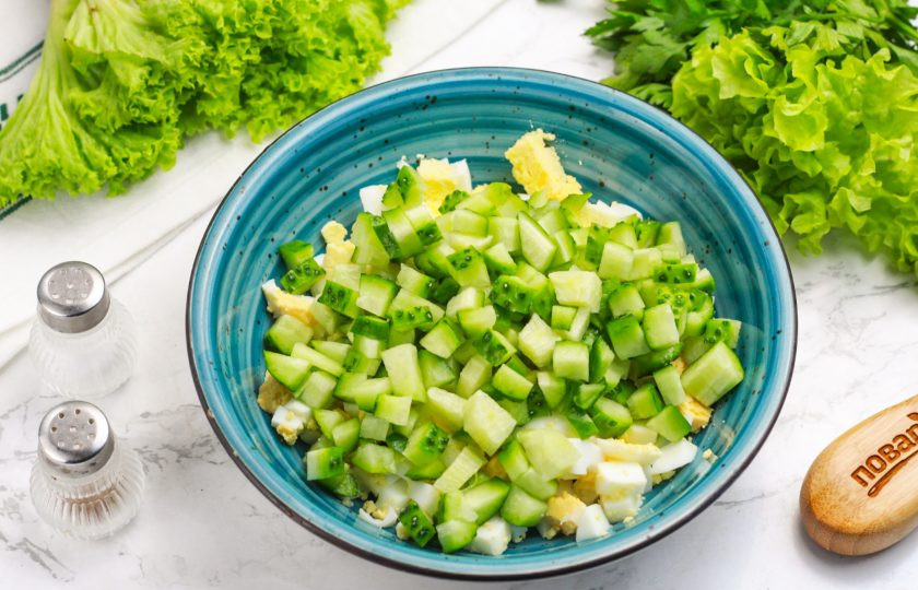 1. Этап. Салат с огурцом, сыром и тунцом: Промойте огурцы, срежьте хвостики и нарежьте такими же кубиками, как и яйца. Добавьте в емкость.