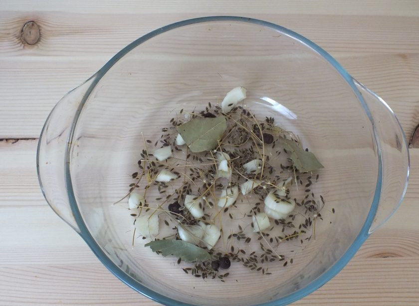 1. Этап. Засолка опят горячим способом: Возьмите глубокую тару. На дно поломайте половину количества укропных зонтиков, нарежьте 1 зубчик чеснока, половину количества душистого перца, лавровый лист.