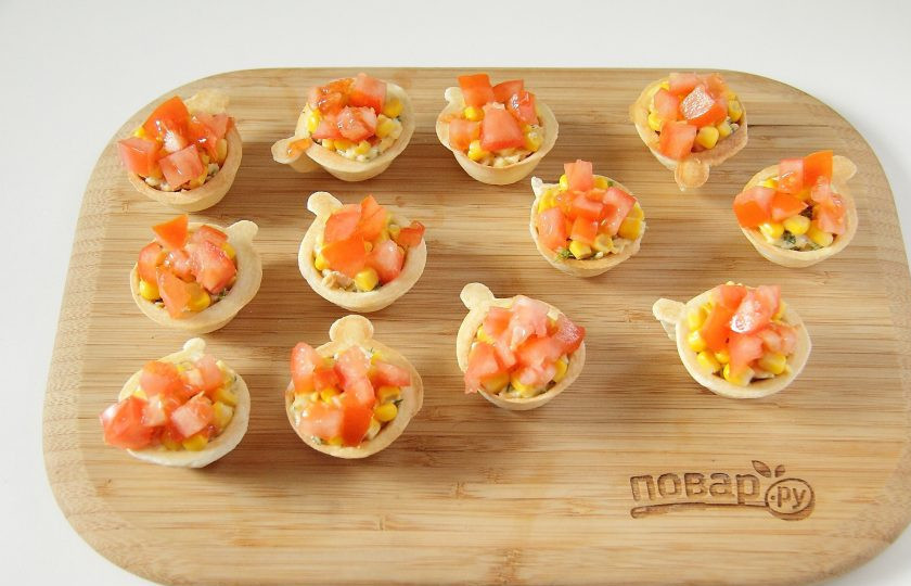 1. Этап. Запеченные тарталетки с курицей: Помидоры нарежьте небольшими кубиками и выложите произвольно на кукурузу.