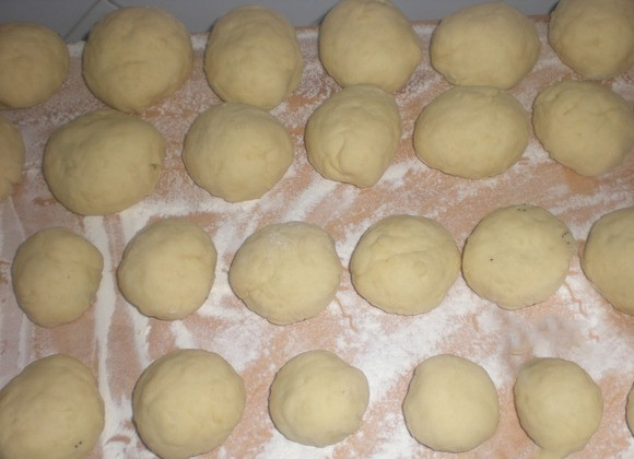 1. Этап. Пончики с маком: Тесту даем 1,5 часа, чтобы оно успело вступить в реакцию с дрожжами. После делим его на маленькие части, из которых формируем маленькие пухлые лепешки. Закладываем в каждую лепешку нашу начинку, закрываем края и формируем шарики.