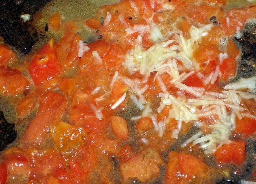 1. Этап. Суп из морского окуня: В это время готовим заправку. На сковородку выливаем несколько ложек оливкого масла, затем в нем обжариваем помидор, очищенный от кожуры и зерен. К нему добавляем натертый чеснок, солим, накрываем крышкой и тушим на медленном огне около 5 минут.