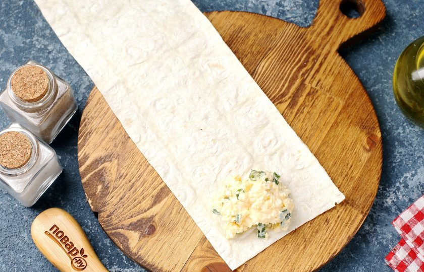 1. Этап. Конвертики из лаваша с варёными яйцами и сметаной: На каждую полоску лаваша с одного края выложите 1-2 ст.л. начинки.