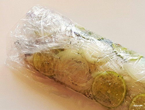 1. Этап. Скумбрия на углях: Рыбу с луком и лаймом хорошенько замотайте в пищевую пленку, положите в тарелку и поставьте в холодильник мариноваться на пару часов. Если есть возможность, то лучше оставить ее в холодильнике на всю ночь.