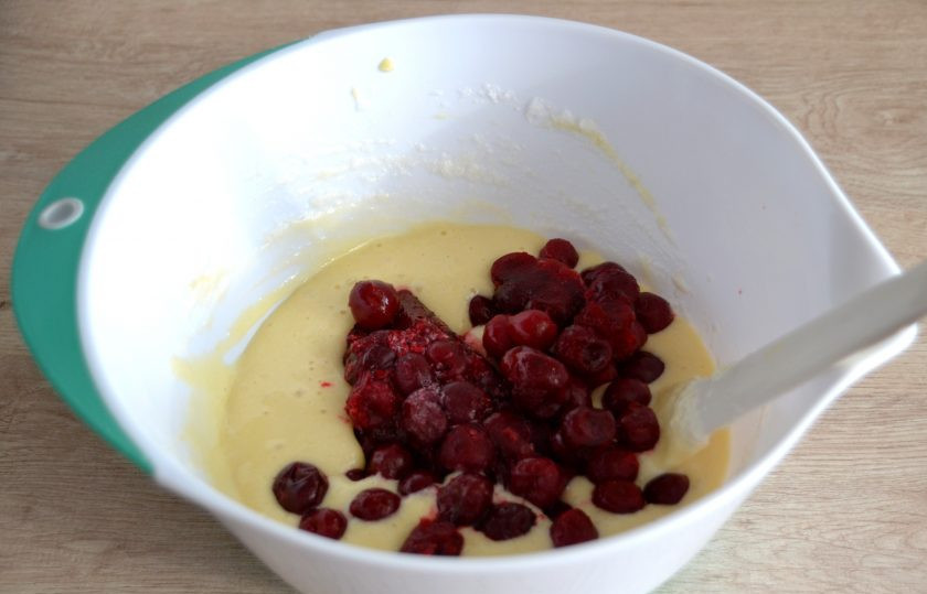 1. Этап. Шарлотка с абрикосами и вишней: В 2-3 приема введите белки в тесто, вмешайте силиконовой лопаточкой движением снизу вверх до однородности. Всыпьте мороженую вишню, вмешайте в тесто. Но можно поступить другим способом, выложите половину теста, на него вишню, а затем вторую половину теста. Так тесто меньше окрасится вишневым соком.