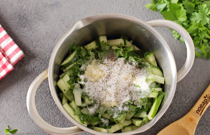 1. Этап. Салат из огурцов с чесноком на зиму: Переложите огурцы в глубокую емкость. Добавьте зелень, чеснок, масло, уксус, соль и перец.