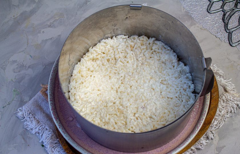 1. Этап. Салат с копченой курицей, черносливом и грецкими орехами: Соберите салат в сервировочном кольце, на данное количество ингредиентов, понадобится кольцо диаметром 14-16 см. Установите кольцо на плоское блюдо, на дно выложите первым слоем рис и плотно его утрамбуйте.