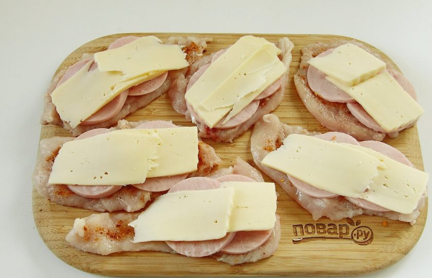 1. Этап. Куриные роллы с ветчиной и сыром: 4. Часть сыра натрите на терке, остальную часть нарежьте тонкими ломтиками и выложите на ветчину.