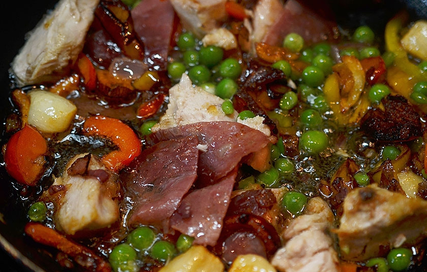 1. Этап. Паэлья с цыпленком и чорризо: 6. Добавьте в сковороду нарезанную чорризо и горошек.