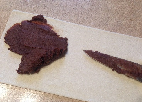 1. Этап. Печенье Слоновьи ушки: Выкладываем на один лист теста треть шоколадной помадки, размазываем её ножом по всей поверхности.