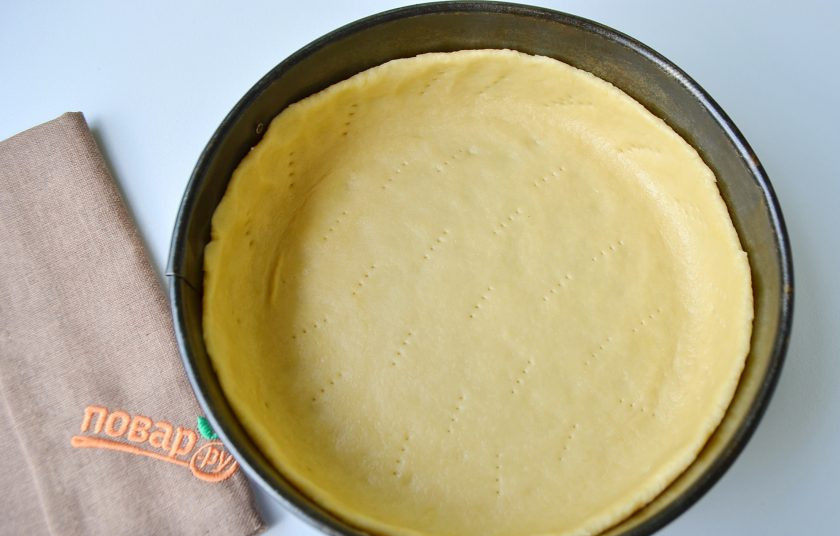 Вишневый тарт с творогом 1. Этап. Вишневый тарт с творогом: 2. На рабочем столе раскатайте тесто чуть больше диаметра формы. С помощью скалки перенесите его в смазанную маслом форму. Проколите вилочкой. Уберите форму с тестом в морозилку на 15 минут.