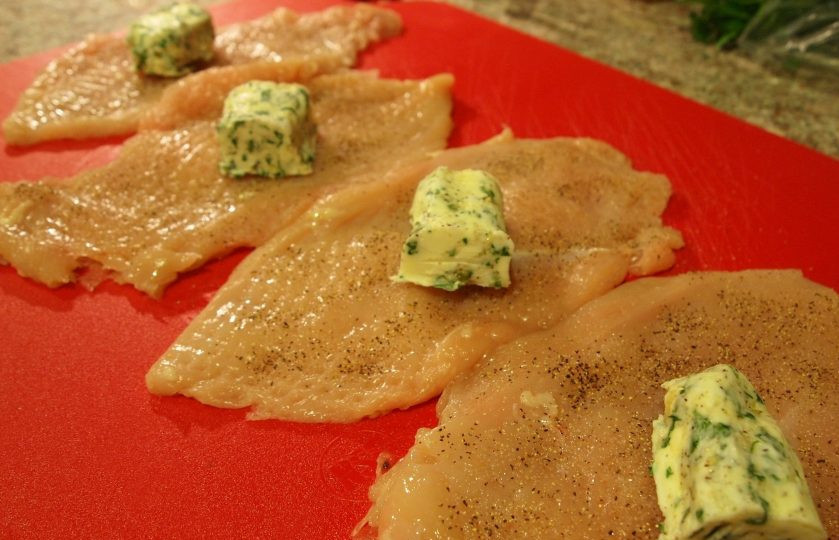 1. Этап. Самые ленивые Котлеты по-киевски: 4. Каждое филе разрежьте вдоль на 2 части, затем накройте его пленкой и отбейте, посолите и поперчите. Достаньте масло из морозилки и разрежьте на 4 части, выложите каждый кусочек по центру.