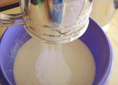 1. Этап. Пышки на сгущенке: Берем муку (количество – на глаз, сколько заберет жидкость), добавляем в нее соль с разрыхлителем и вот так все вместе просеиваем в емкость со взбитыми яйцами и молоком.