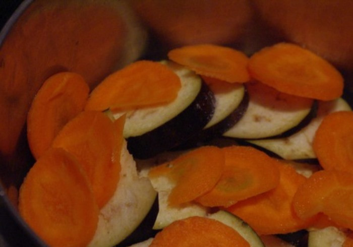 1. Этап. Гарнир к куриным котлетам: Порежьте баклажаны и морковь тонкими кружками. Выложите на дно кастрюли слой из половины баклажан, а на них слой из половины моркови. Немного подсолите.