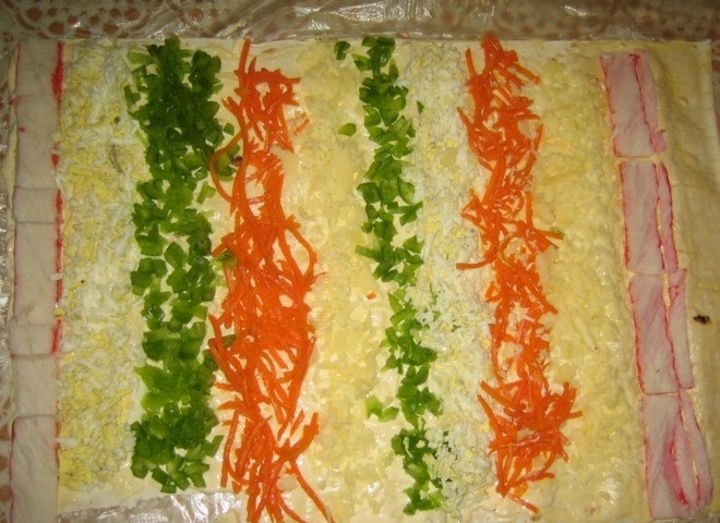 1. Этап. Рулет из крабовых палочек в лаваше: Перец нарежьте мелкими кубиками. Яйца почистите и нашинкуйте. Сыр натрите на крупной тёрке. Крабовые палочки разрежьте вдоль. Выложите ингредиенты слоями по всему лавашу, как на фото.